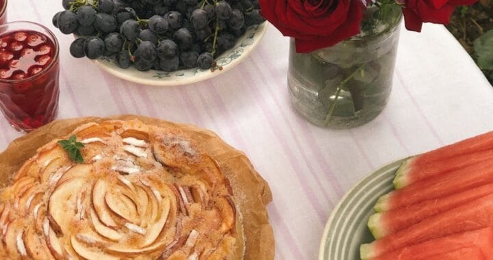 Vibrant summer table setting with fruit, flowers, and pie for a celebratory feast.
